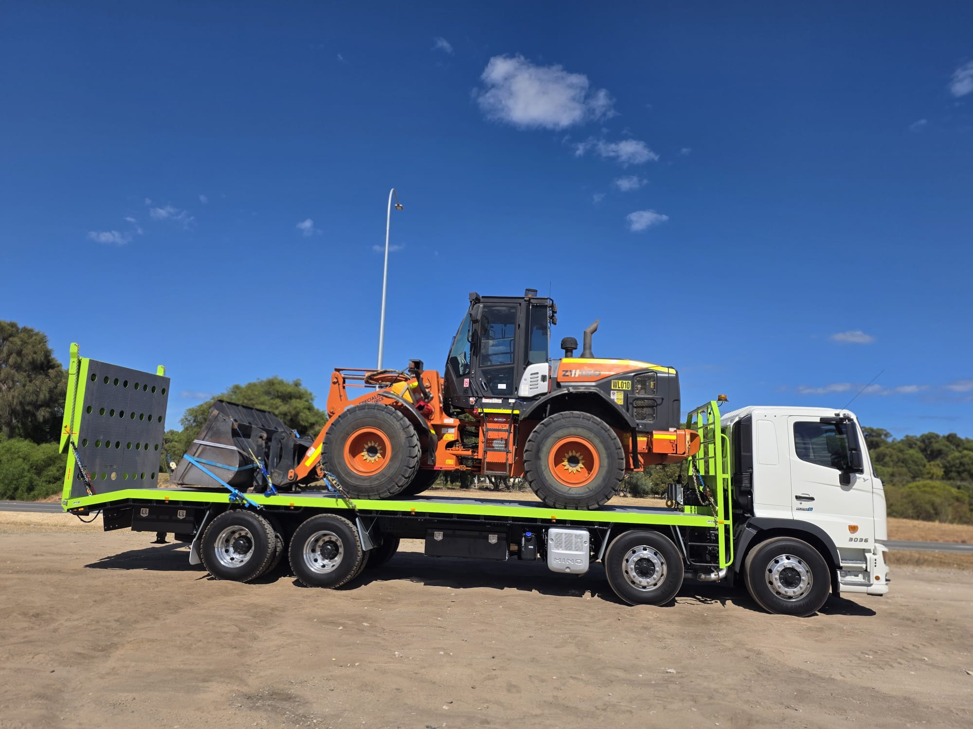 Wheel loader loaded on Ozwest flatbed truck for transport across Western Australia